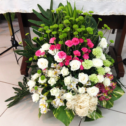 Basket of white roses, fuchsia carnations, green carnations, green buttons